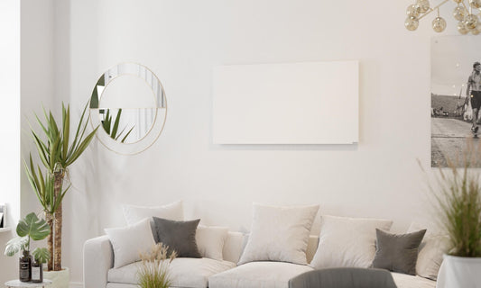 woonkamer met bank, planten en infraroodpaneel aan de muur
