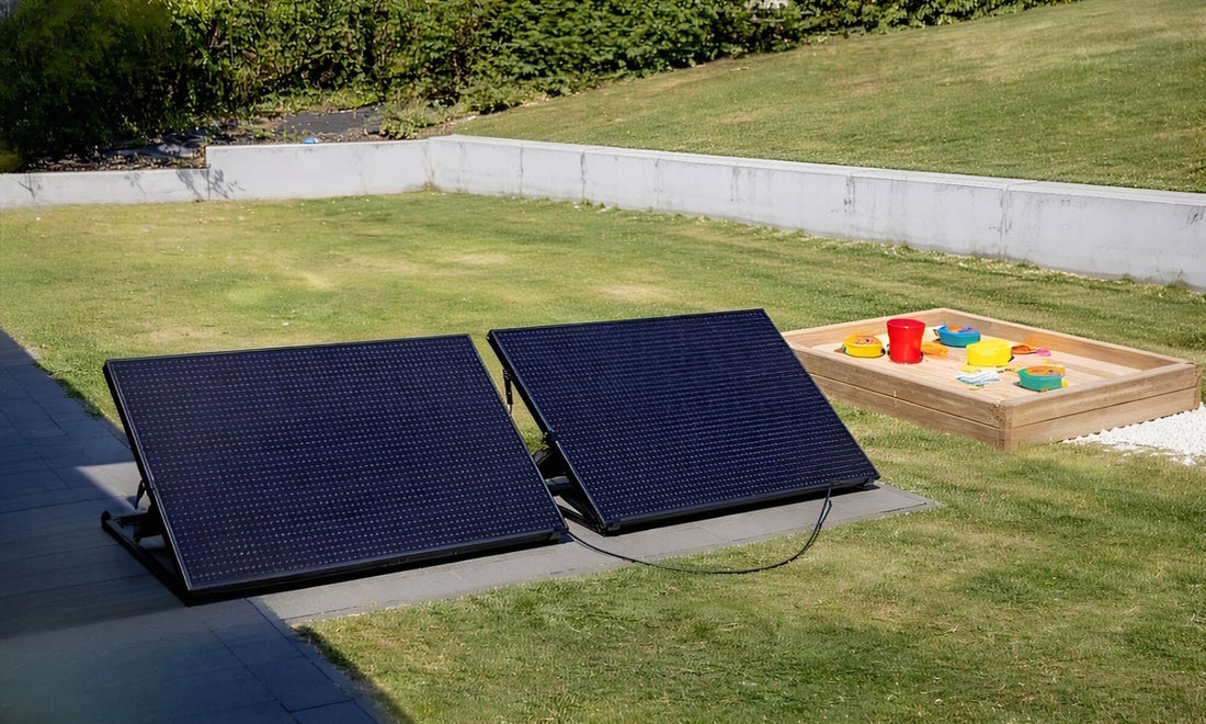 twee zonnepanelen op standaard geplaatst op gras in een tuin met zandbak op de achtergrond