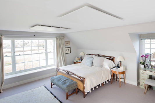 slaapkamer met bed en twee infraroodpanelen tegen het plafond bij groot raam