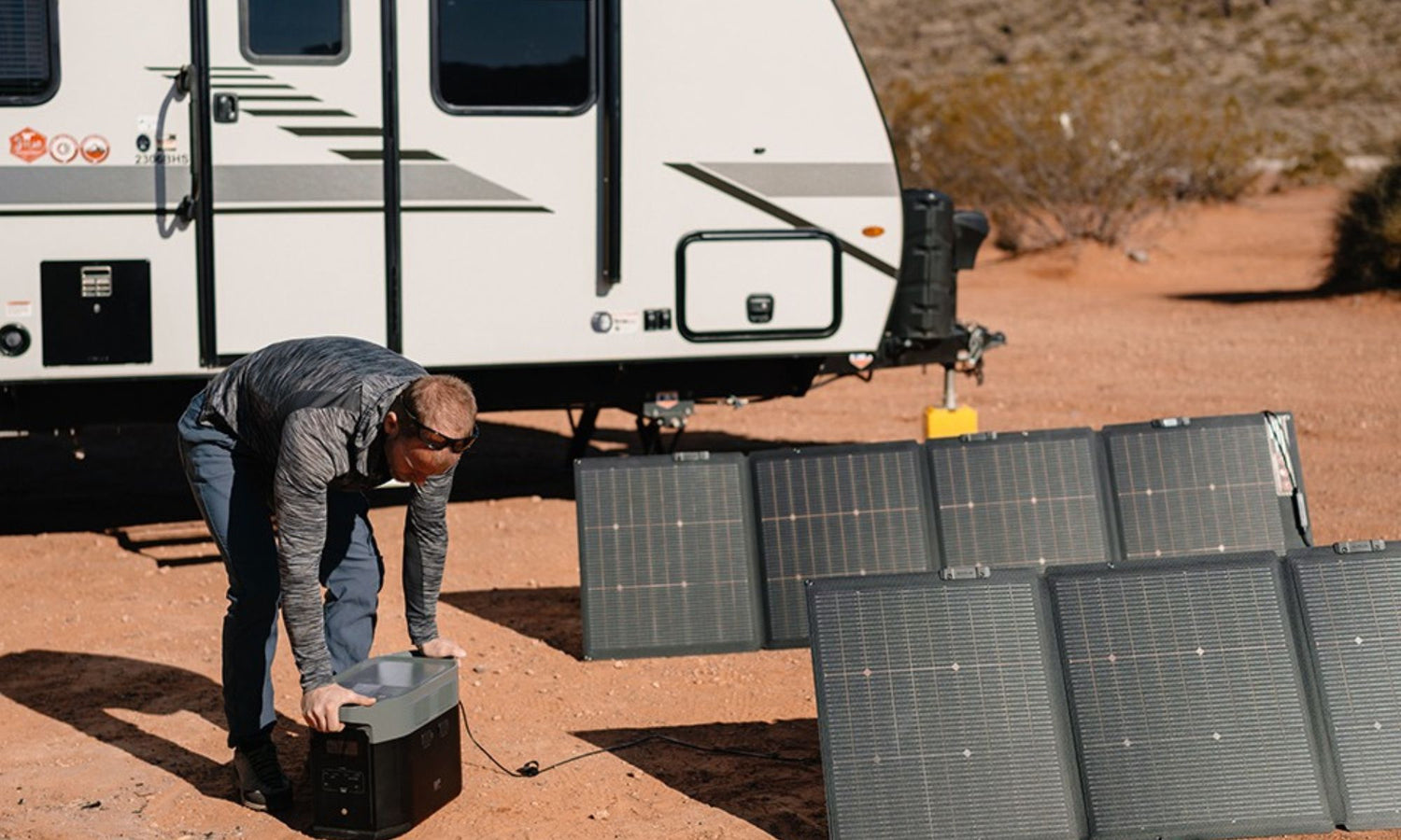 Draagbaar zonnepaneel opgesteld naast camper met power station in droge buitenomgeving