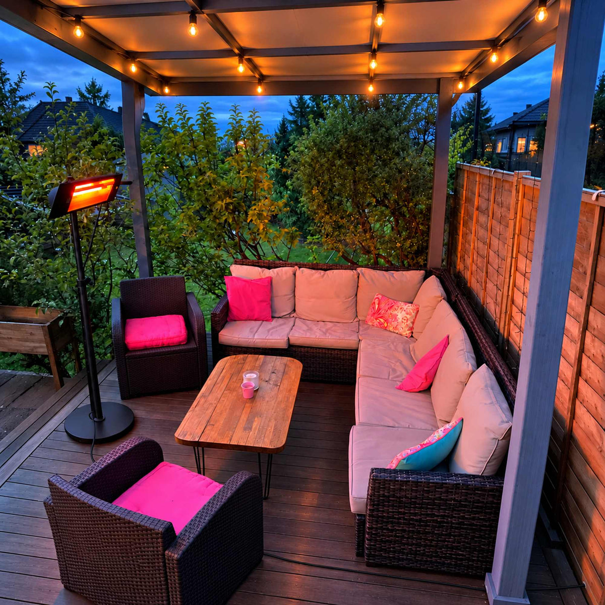 Zwarte Herschel COLORADO 2500 W infrarood terrasverwarmer op zwarte standaard naast een loungeset met roze kussens