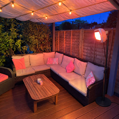Witte Herschel MIAMI 2000 W infrarood terrasverwarmer op zwarte standaard naast een loungehoek onder een luifel