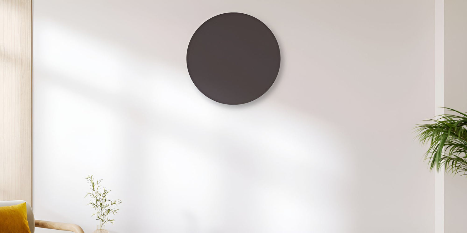 Rond grijs Herschel Select XLS infraroodpaneel op witte muur in een woonkamer