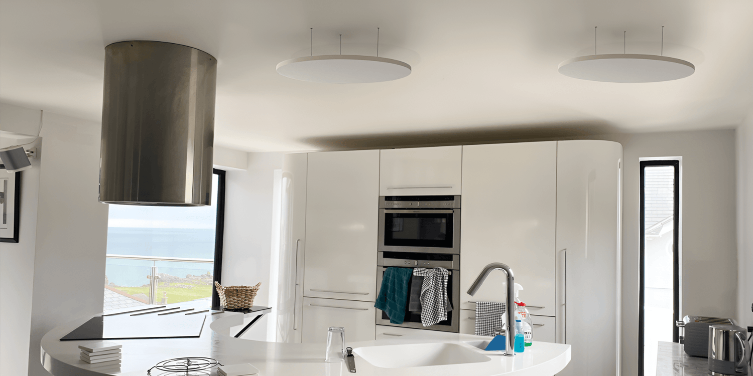 Twee witte ronde Herschel Select XLS infraroodpanelen gemonteerd aan het plafond in een moderne witte keuken