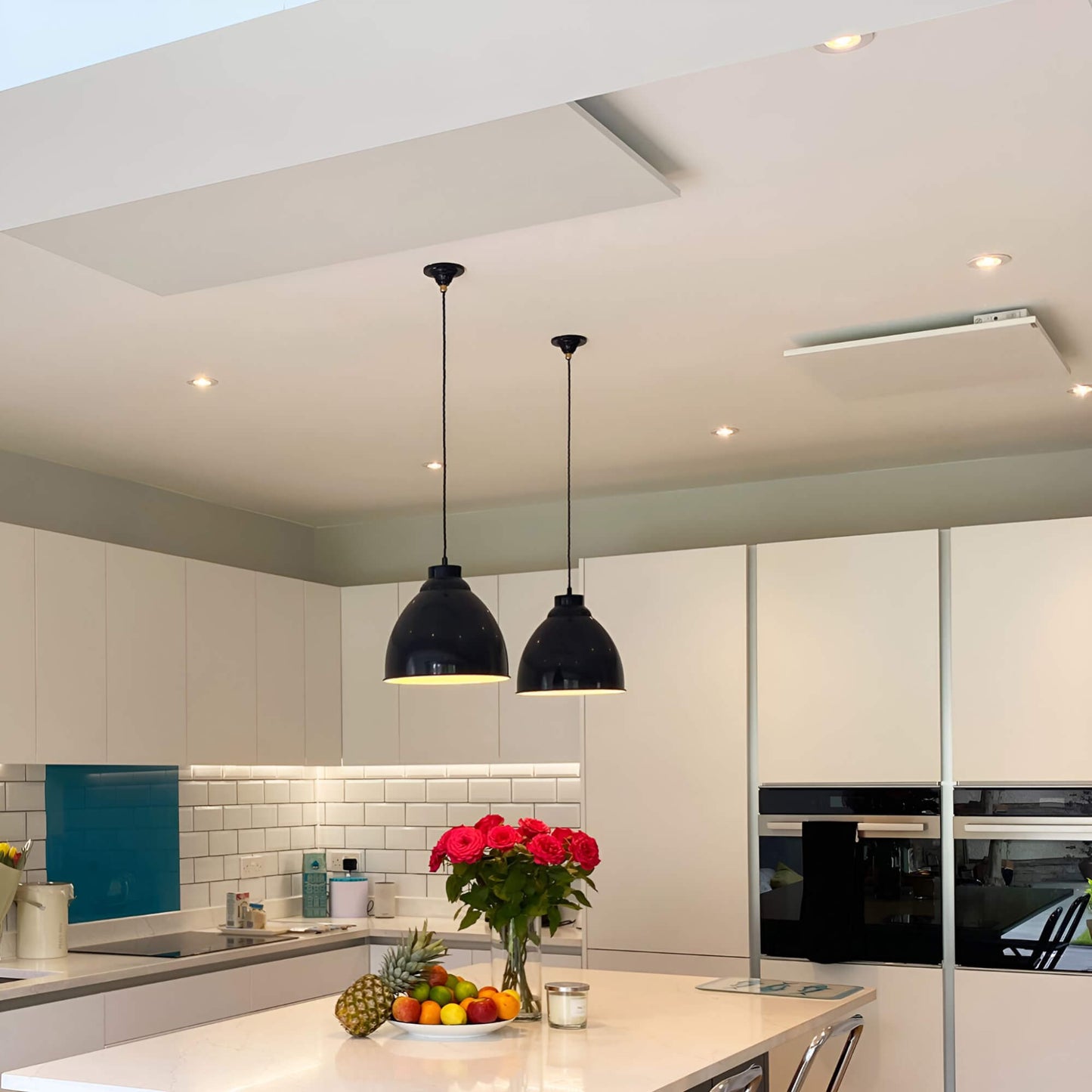 2 witte infraroodpanelen aan plafond in moderne keuken met kookeiland en verlichting
