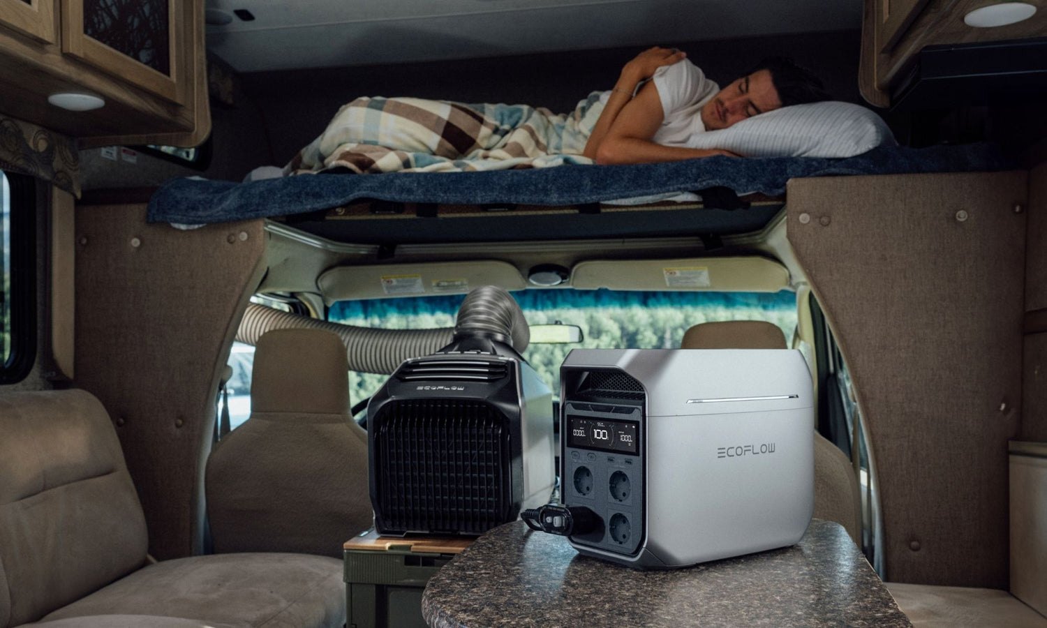 Power station en draagbaar apparaat op tafel in een camper met persoon die slaapt op het bovenbed